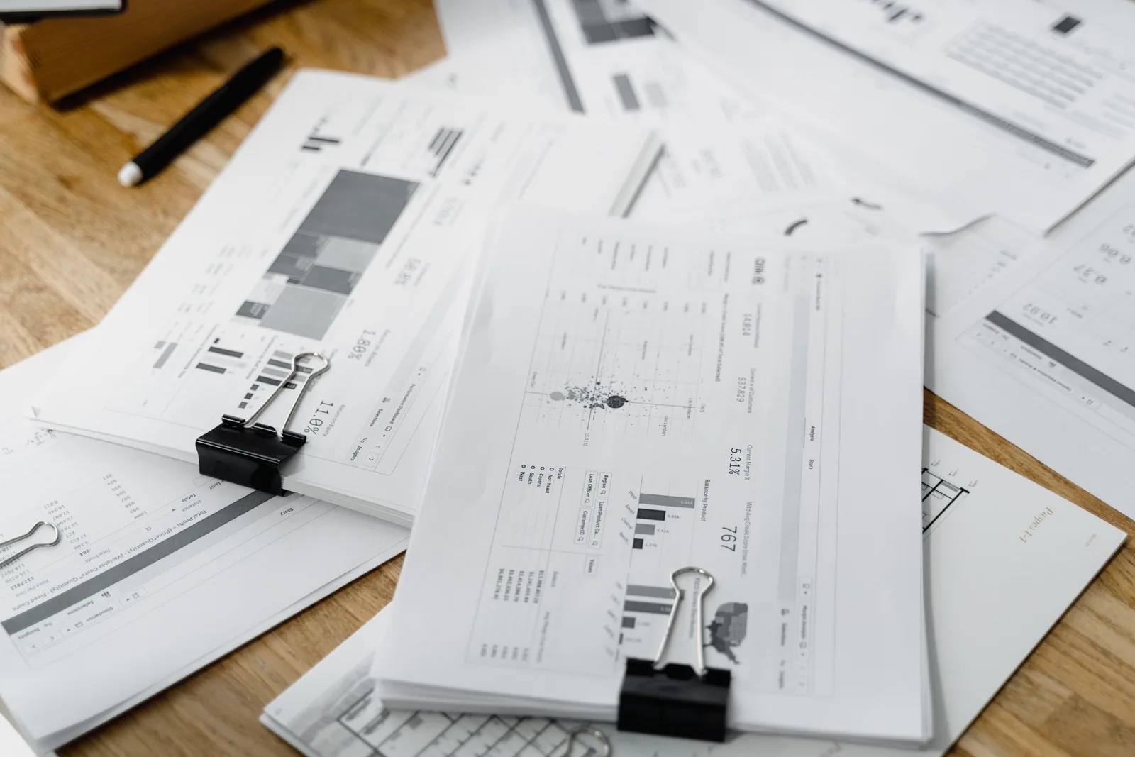 A stack of financial reports and graphs with clips on a wooden desk, highlighting business planning. Membership site marketing benchmarks: why comparisons vary