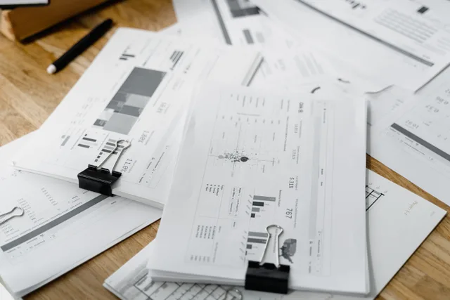 A stack of financial reports and graphs with clips on a wooden desk, highlighting business planning. Membership site marketing benchmarks: why comparisons vary