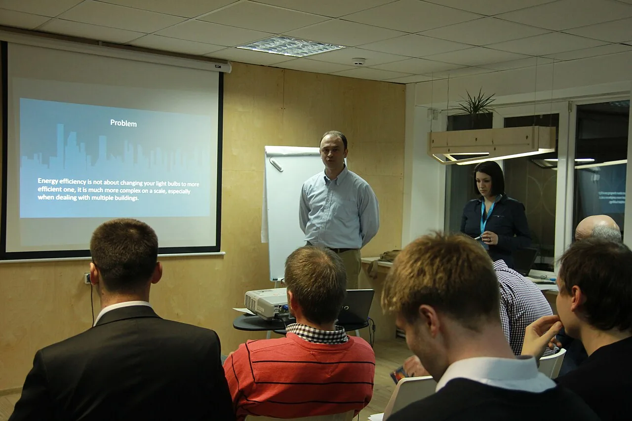A startup team presents a problem slide to an audience during a demo day.